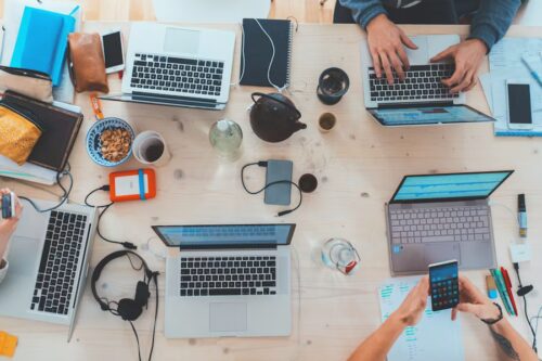 Travail collaboratif avec plusieurs ordinateurs et freelances autour d'une table